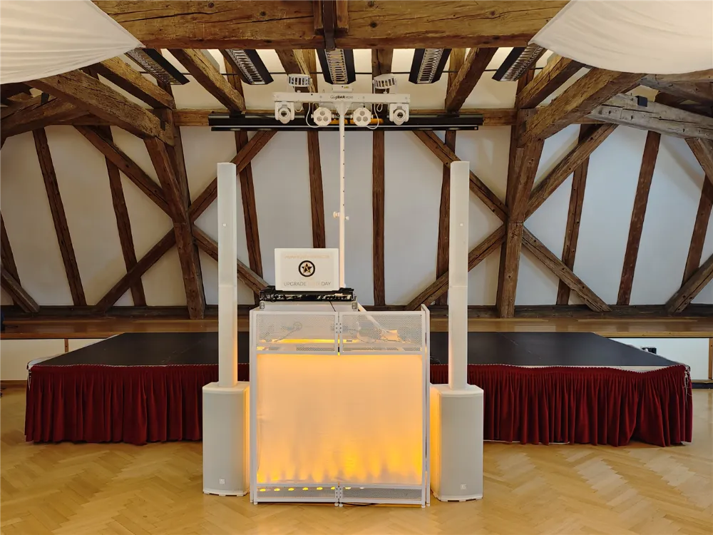 Weißes GOLD-Setup mit hinterleuchtetem DJ-Tisch, zwei Säulen-PAs und einer Lichtanlage vor der Bühne im Lenausaal Z2000 in Stockerau